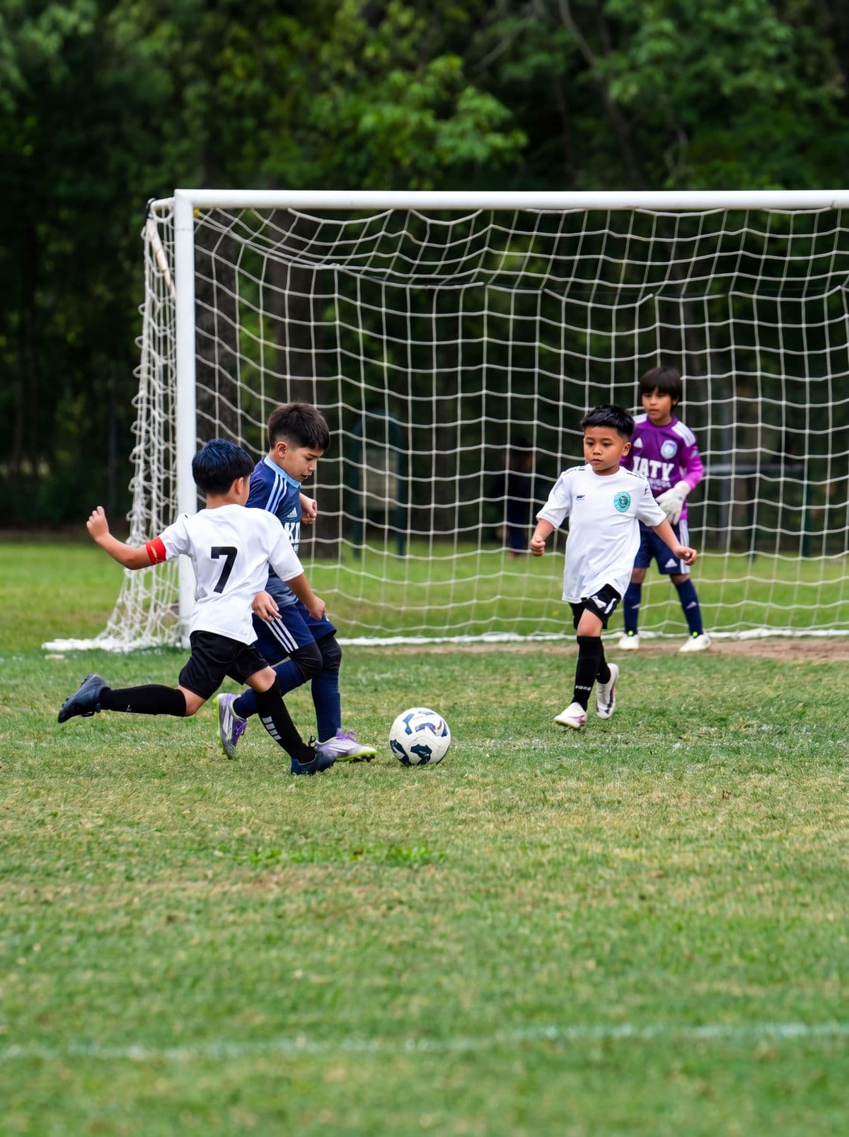A NEXO player in white strikes the ball toward goal during a youth match